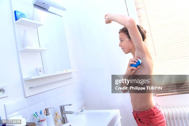 france, young boy in the bathroom using spray. - boy armpit stock-fotos und bilder