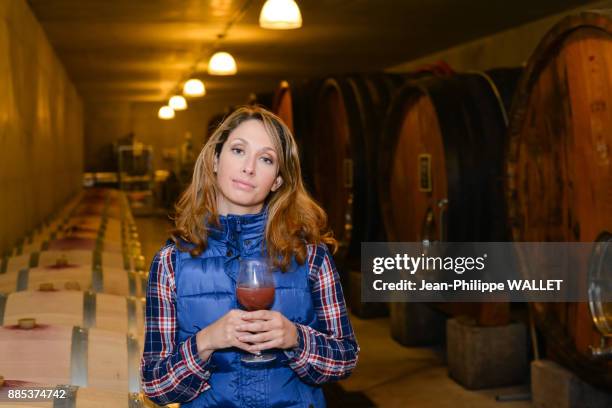 cheerful young woman oenologist tasting a glass of wine in cellar with wine barrel in background- cepage grenache, chateauneuf du pape, cotes du rhone, france - chateauneuf du pape stock pictures, royalty-free photos & images