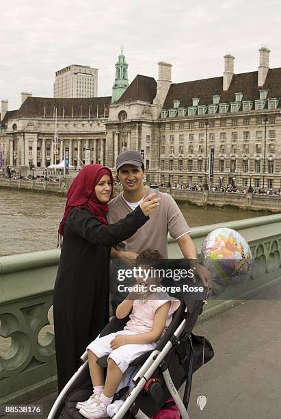 Muslim family takes a self-portrait picture of themselves with Thames River with the Marriott County Hall Hotel in the background as seen in this...