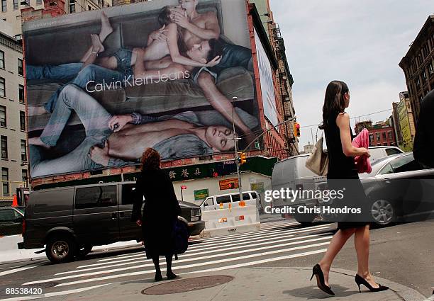 Pedestrians and cars pass near a Calvin Klein billboard on the side of a building June 17, 2009 in the SoHo neighborhood of New York City. The...