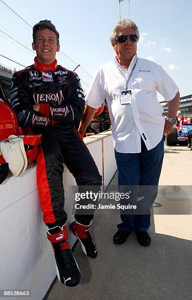 Marco Andretti, driver of the Team Venom Andretti Green Racing Honda Dallara, looks on with his grandfather and racing legend Mario Andretti during...