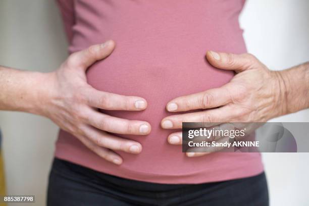 two hands of different people on the belly of a pregnant woman. - surrogato foto e immagini stock