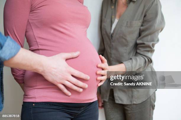 closeup of a human hand and a woman on the belly of a pregnant woman 6 months - gestational surrogacy stock pictures, royalty-free photos & images