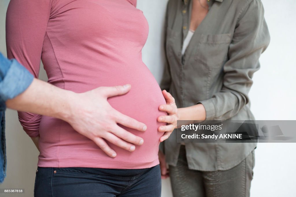 Closeup of a human hand and a woman on the belly of a pregnant woman 6 months