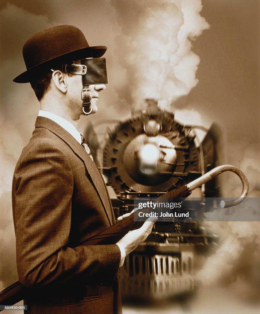Blinkered businessman on railway, train approaching (Composite)