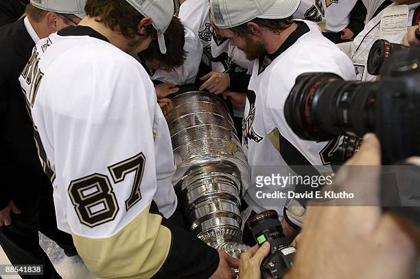 Pittsburgh Penguins Sidney Crosby , Matt Cooke , and Petr Sykora victorious, looking for Sykora's name on Stanley Cup trophy during celebration after...
