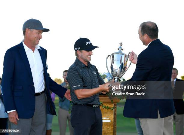 Austin Cook is presented the winners trophy on the 18th green after the final round of The RSM Classic at the Sea Island Resort Seaside Course on...