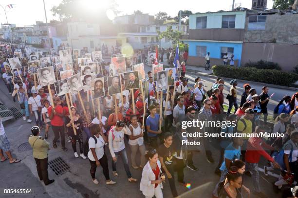 Cubans hold photos of late Cuban Revolution leader Fidel Castro during a march from the Revolution square to the Santa Ifigenia cemetery, as Cuba...