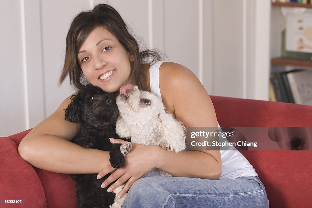 Woman on couch hugging dogs