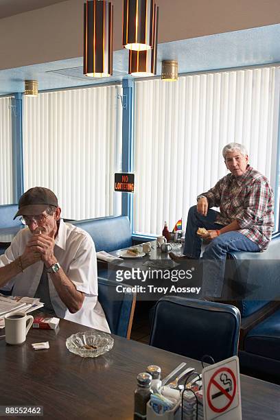 man lighting cigarette in no smoking section of diner - man eating at diner counter foto e immagini stock
