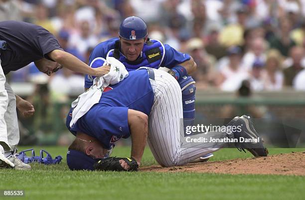 Pitcher Jason Bere of the Chicago Cubs is helped by the trainer as he lay injured while catcher Todd Hundley looks on against the Cincinnati Reds...