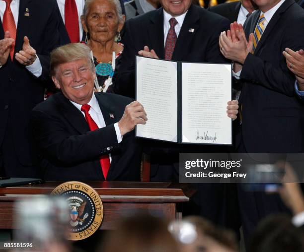 With Utah officials surrounding him, U.S. President Donald Trump shows an executive order he signed reducing the Grand Staircase-Escalante National...