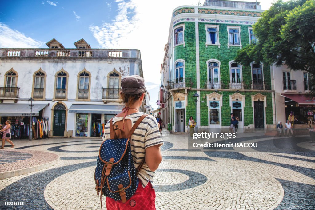 Young woman from behind, observed the square of the town of Burgau, Algarve region, Portugal