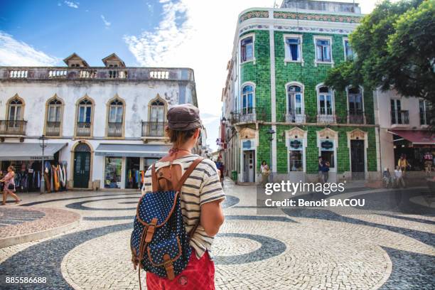 young woman from behind, observed the square of the town of burgau, algarve region, portugal - algarve stock pictures, royalty-free photos & images