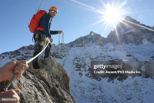 mountaineer reaches summit, looks back to belayer - climber hands bildbanksfoton och bilder