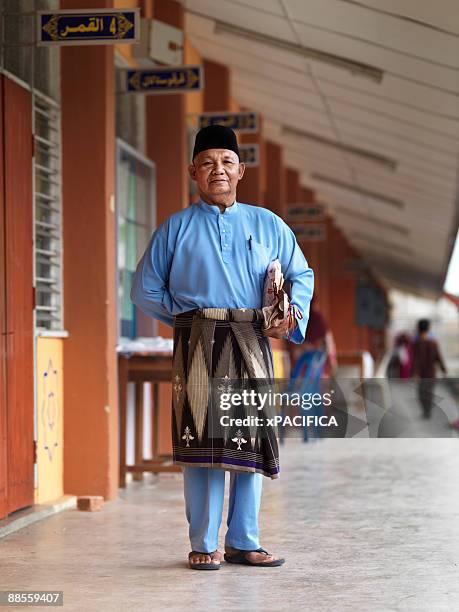a stand posing in his traditional garb.  - malaysian culture stock-fotos und bilder