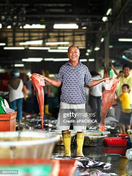 a fishmonger showing off his prize fish. - 魚市場 ストックフォトと画像