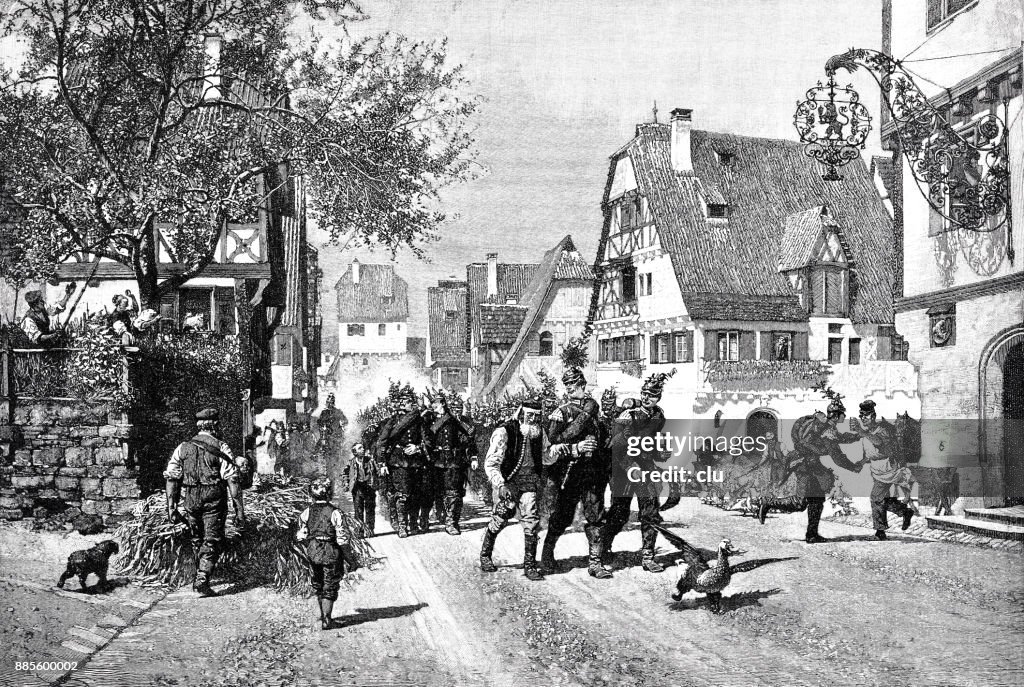 A troop of soldiers marches through a village
