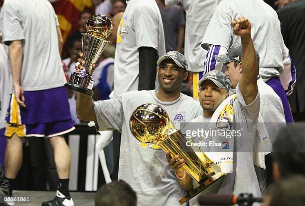 Kobe Bryant of the Los Angeles Lakers holds the Bill Russell MVP trophy and Derek Fisher of the Lakers holds the Larry O'Brien trophy after defeating...