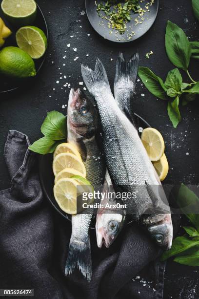fresh fish with lemon, spices and herbs ready for cooking on dark background - catch of fish stock pictures, royalty-free photos & images