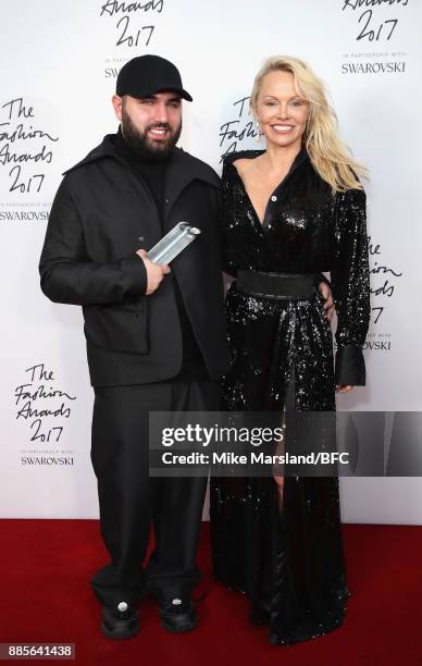 Michael Halpern poses in the winners room wins the British Emerging Talent Womenswear Award presented to him by Pamela Anderson during The Fashion...