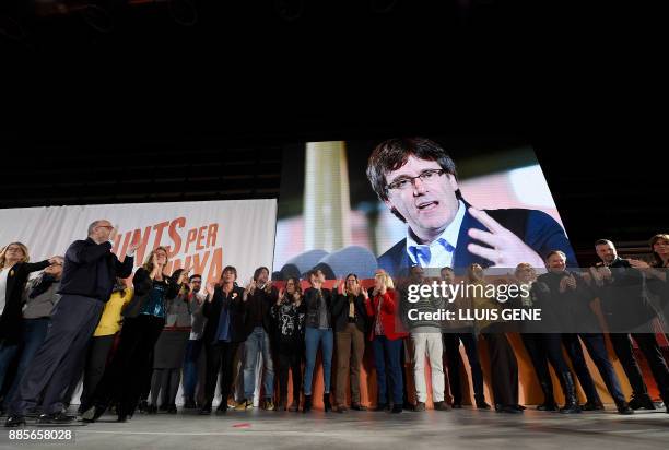 Candidates and members of 'Junts per Catalonia' grouping applaud under a picture of their cadidate for the upcoming Catalan regional election, Carles...