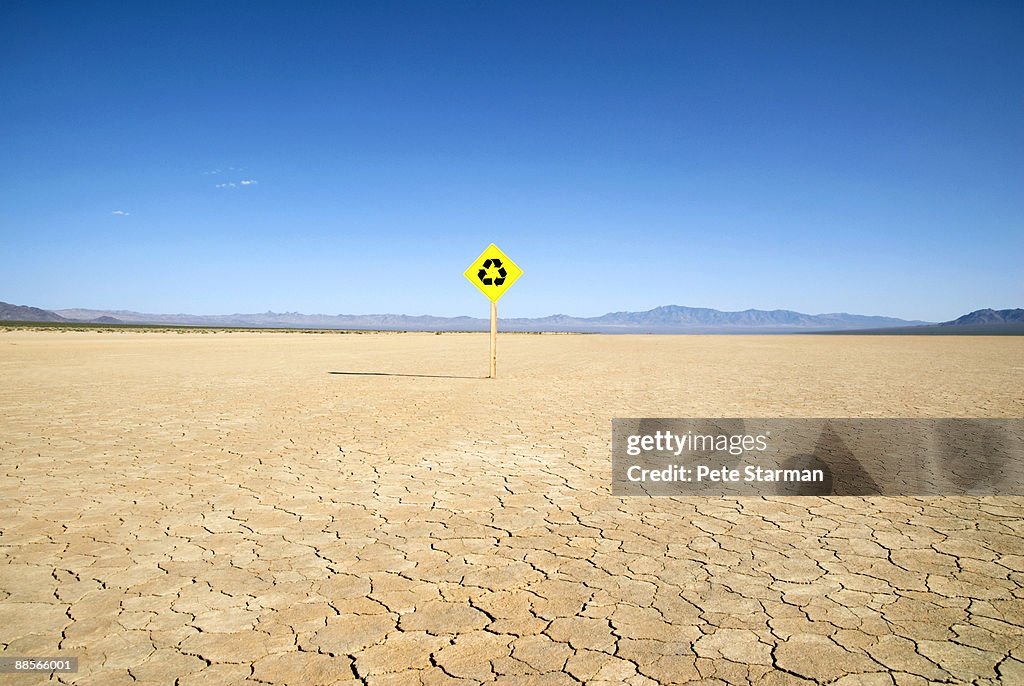 Recycle traffic sign on dry lake bed. 