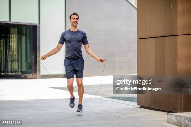 mann mit seil springen im freien training - seilspringen stock-fotos und bilder