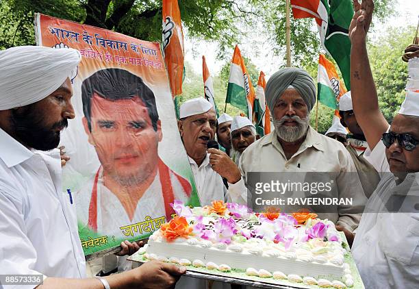 Congress Party supporters cut a cake as they celebrate Congress Party General Secretary Rahul Gandhi's 40th Birthday in front of Congress Party...