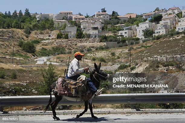 Palestinian man rides his donkey past the West Bank Jewish settlement of Elazar, about 20 kms south of Jerusalem, on June 19, 2009. Israelis...