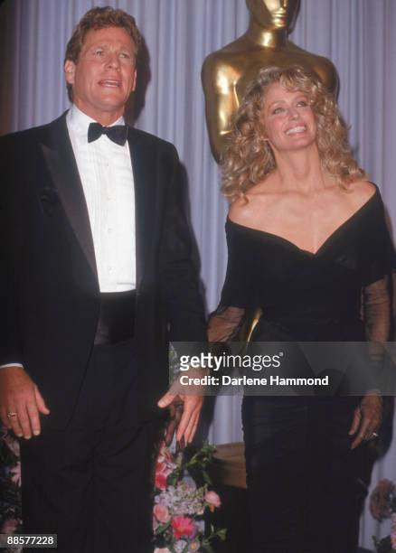 American acting couple Ryan O'Neal and Farrah Fawcett hold hands as they announce the winner of the Oscar for Film Editing at the 61st Annual Academy...