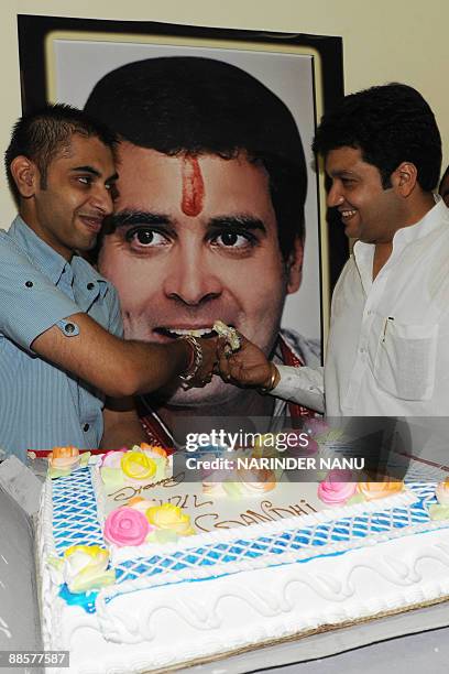 Members of the Youth Congress Party offer cake to a poster of Congress Party General Secretary Rahul Gandhi in celebration of his 40th birthday in...