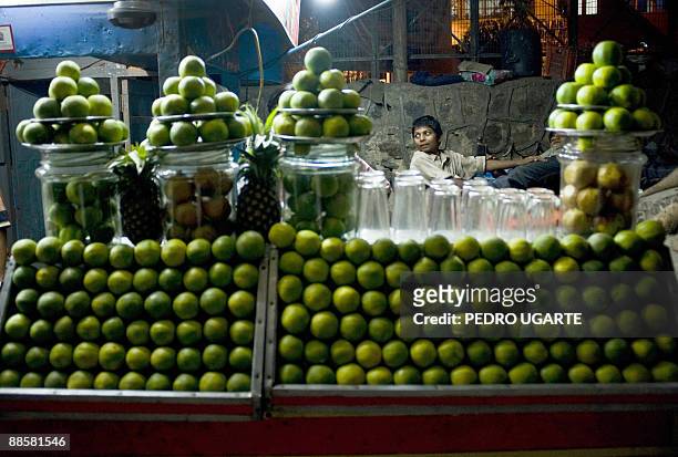 An Indian kid is seen behind a stall offering orange juice in New Delhi on June 19, 2009. India's annual inflation rate slipped into negative...