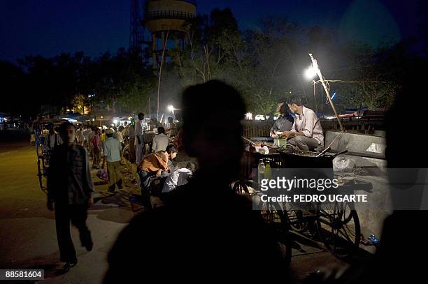 Indian street sellers wait for costumers at night in a street of New Delhi on June 19, 2009. India's annual inflation rate slipped into negative...