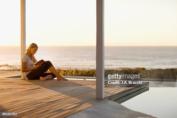woman sitting on deck near ocean - escapism reading stock pictures, royalty-free photos & images