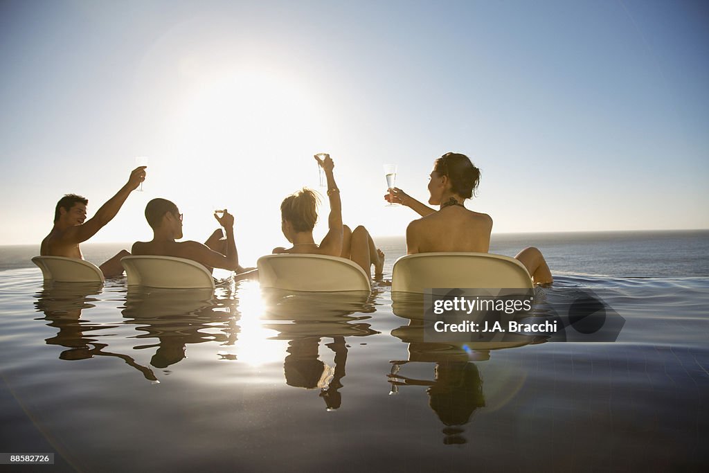 Friends drinking in infinity pool near ocean