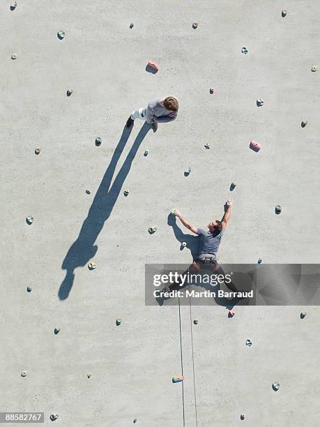 businessman standing on rock climbing wall - out of context foto e immagini stock