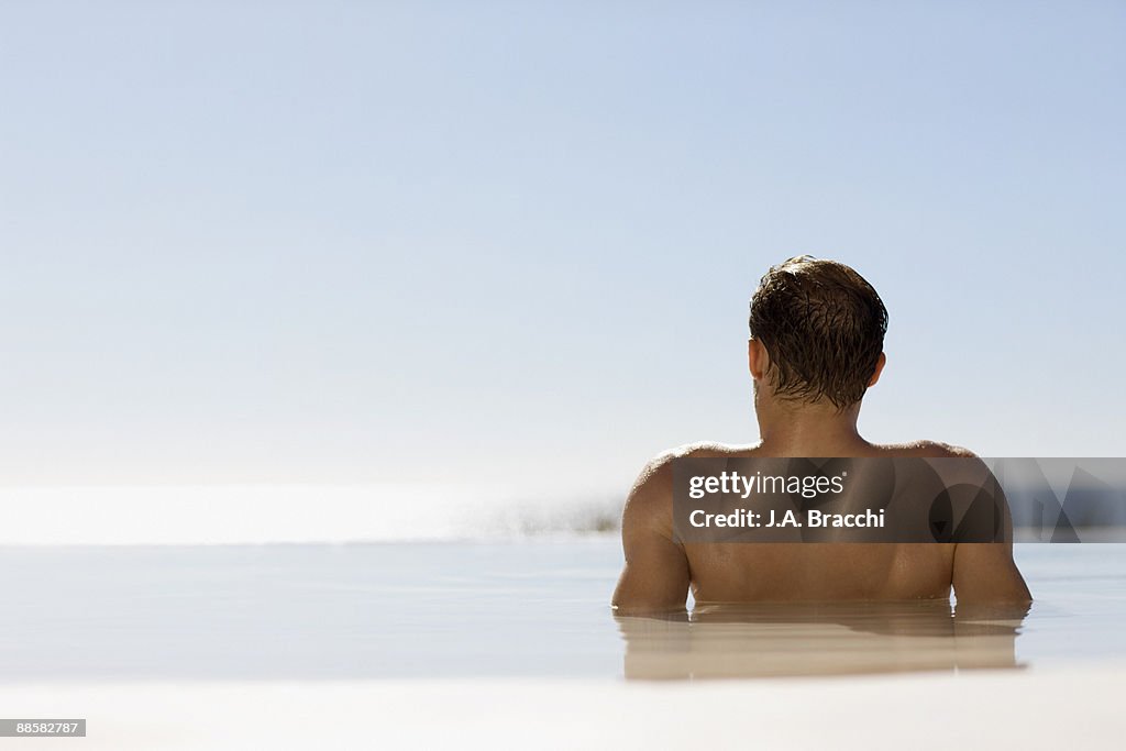 Man soaking in infinity pool