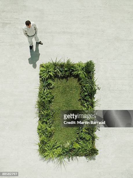 man viewing lush lawn in cement courtyard - vertical foto e immagini stock