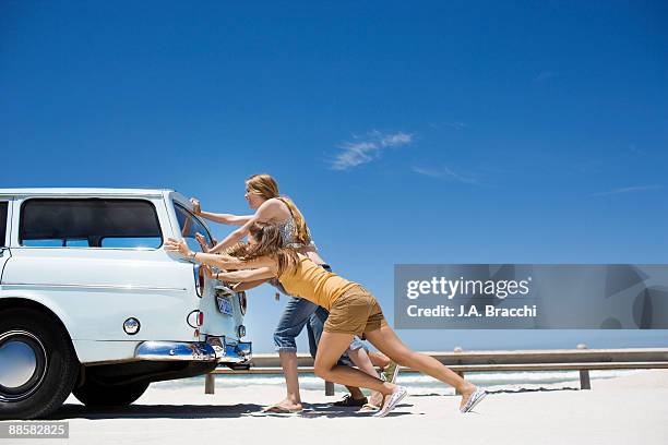 people pushing broken down car at beach - empurrar imagens e fotografias de stock