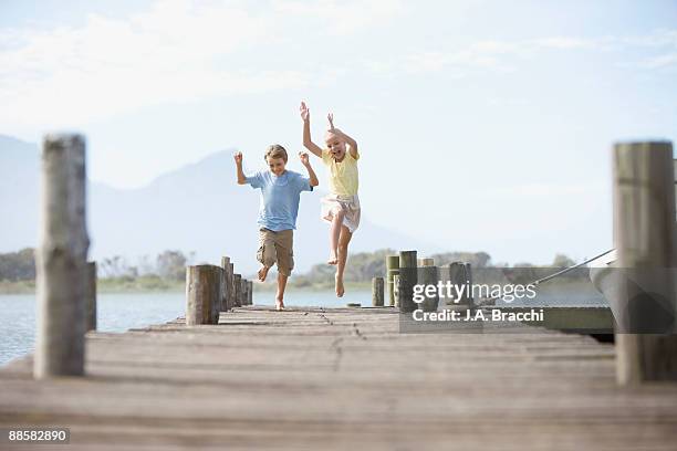 brother and sister running on dock - boy 10 11 barefoot stock pictures, royalty-free photos & images