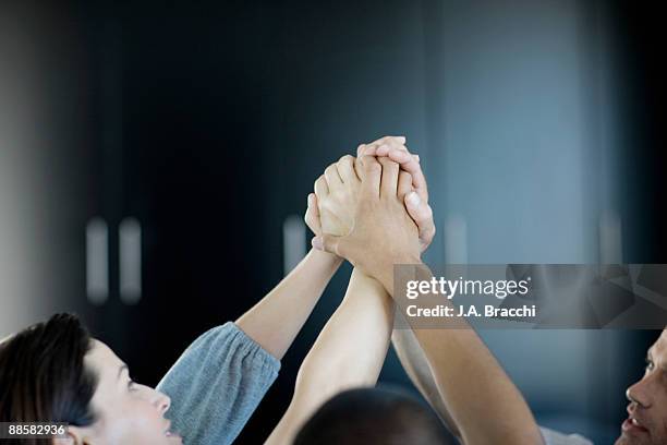 business people holding hands in office - exito fotografías e imágenes de stock