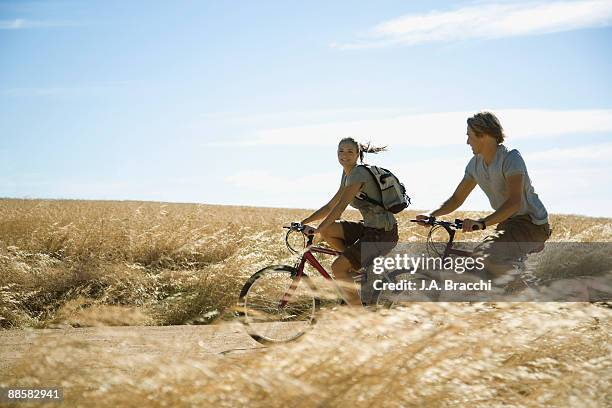 couple riding bicycles through countryside - bicycle and couple stockfoto's en -beelden