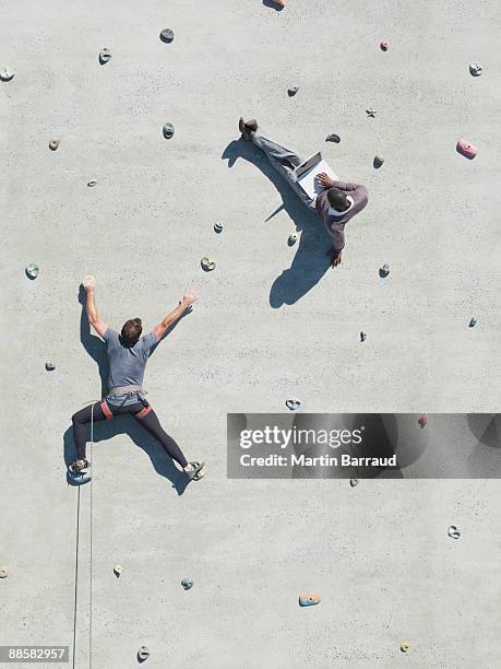 businessman using laptop on rock climbing wall - paroi rocheuse photos et images de collection