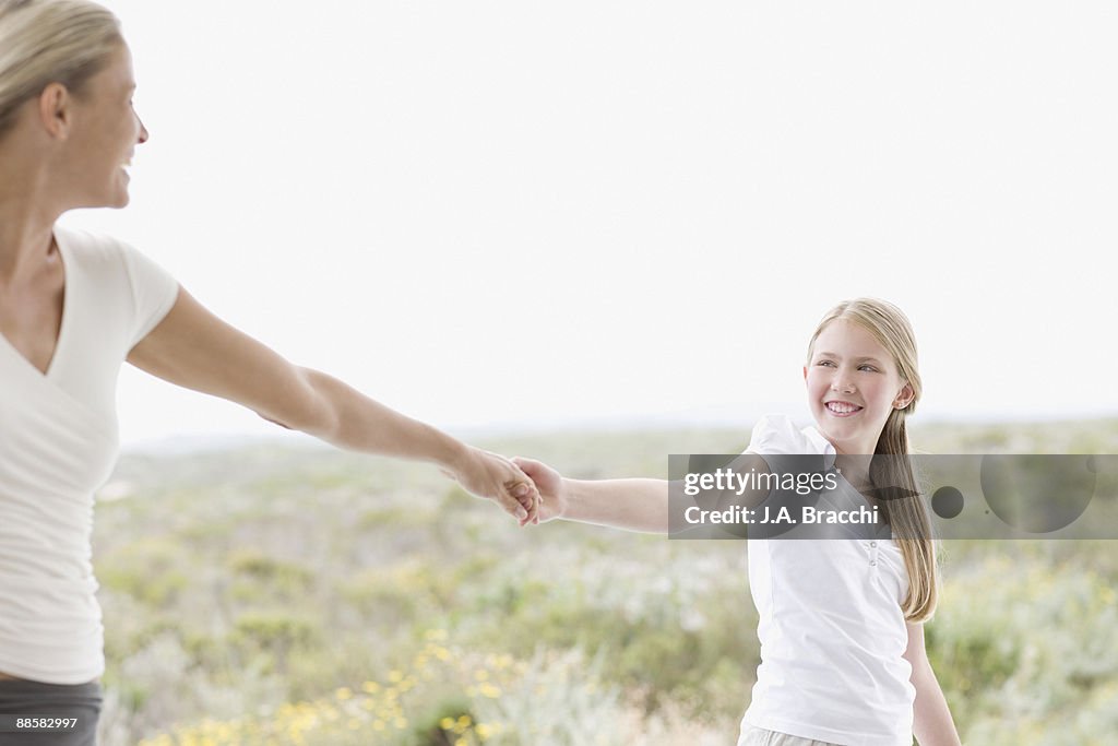 Mother and daughter holding hands outdoors