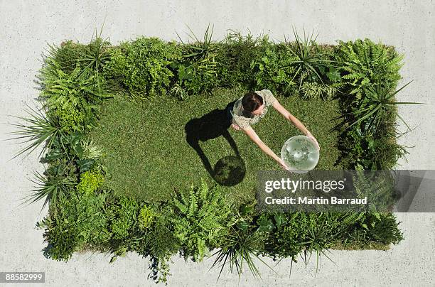 woman holding globe on lush lawn in cement courtyard - ambientalista foto e immagini stock