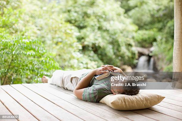 man napping on porch in remote area - outdoor patio stock-fotos und bilder