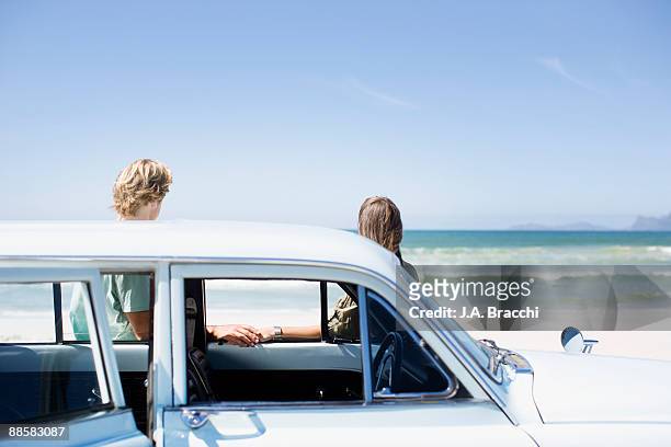 couple leaning on car at beach - holding hands in car stock pictures, royalty-free photos & images