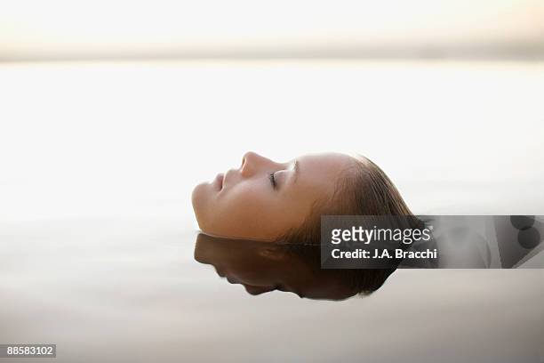 woman soaking in swimming pool - tranquility stock-fotos und bilder