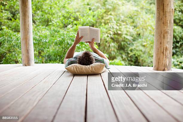 man reading on porch in remote area - reading stock-fotos und bilder